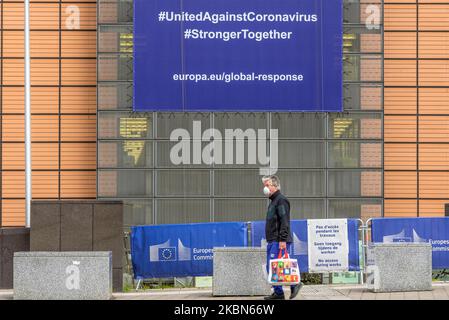 A men is seen walk in front of the Berlaymont building wearing a protective masks where the European Commission headquarters is in Brussels, Belgium 01 May 2020. New banner about the coronavirus global response, In order to contain the spread of Coronavirus ( COVID-19) globle response. (Photo by Jonathan Raa/NurPhoto) Stock Photo