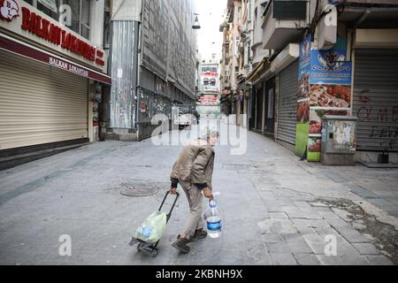An old woman carries water on empty Istiklal Street during the curfew in Istanbul, Turkey on May 09, 2020. Turkey has reimposed a 48-hour curfew in 24 provinces beginning at midnight as part of measures to stem the spread of the novel coronavirus, the country’s Interior Ministry announced. (Photo by Cem Tekke?ino?lu/NurPhoto) Stock Photo