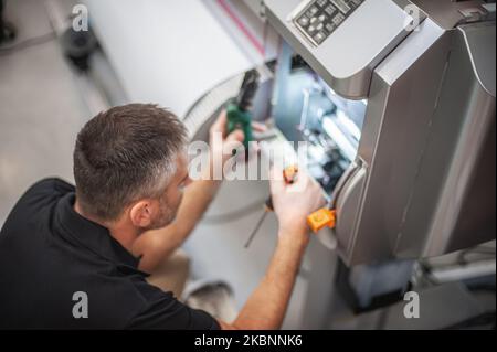 All machines nead maintains. Professional technician troubleshooting and repair the machines in the printing house. Stock Photo