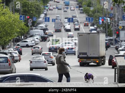 A woman wearing a protective mask walks with her dog in Kyiv, Ukraine, on 13 May, 2020. As on 13 May in Ukraine in total 16,425 laboratory-confirmed cases of the coronavirus COVID-19, including 439 fatal, according the Ukraine's Ministry of Health website. (Photo by STR/NurPhoto) Stock Photo