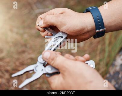 Man hands use multi purpose knife for camping, outdoor survival and adventure in park, woods and scouts hiking. Sharp pocket tool, practical accessory Stock Photo