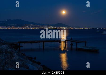 The dazzling Super Flower Moon of May 2020 as seen rising over the Aegean Sea and Thessaloniki city in Greece from Kalochori on May 7, 2020. The rise of last the last supermoon of 2020 appears over the hills of Thessaloniki city, shines bright in the Greek Mediterranean sky and reflects on the sea illuminating the dark night. (Photo by Nicolas Economou/NurPhoto) Stock Photo