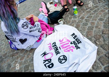 A XR activist is sewing used clothes close to a shirt with a slogan against fashion industry written on it, during a XR action against fast fashion industry in Amsterdam, on May 22nd, 2020. (Photo by Romy Arroyo Fernandez/NurPhoto) Stock Photo
