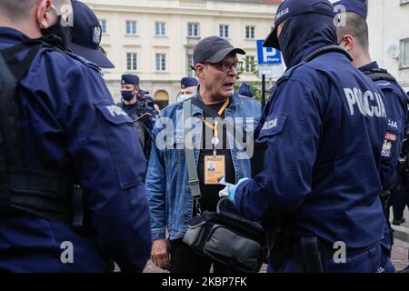 A journalist shows his press card while being held by a cordon of policemen during a demonstration of Entrepreneurs Strike against coronavirus lockdown in the centre of Warsaw, Poland on May 23, 2020. Dozens of journalists were held by police for an hour and some media representatives were threatened with fines for the participation in the demonstration, despite they were at work. The lockdown brought mamy businesses to bankruptcy and increased unemployment in the country. It is a third protest of the businessmen on the streets of Polish capital. In all cases police used force, including gas o Stock Photo
