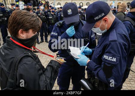 A journalist shows hes press card while being held by a cordon of policemen during a demonstration of Entrepreneurs Strike against coronavirus lockdown in the centre of Warsaw, Poland on May 23, 2020. Dozens of journalists were held by police for an hour and some media representatives were threatened with fines for the participation in the demonstration, despite they were at work. The lockdown brought mamy businesses to bankruptcy and increased unemployment in the country. It is a third protest of the businessmen on the streets of Polish capital. In all cases police used force, including gas o Stock Photo