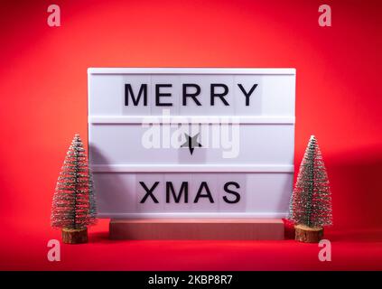 Merry Christmas greetings on lightbox with trees on red Stock Photo