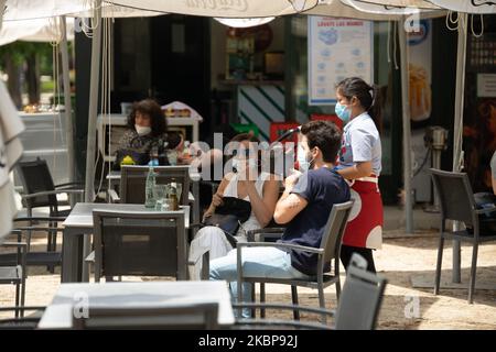 Customers wearing protective face masks sit at an outdoor terrace table of a bar and cafe in Madrid, Spain, on May 25, 2020. Today is the fist day that Madrid passed to the ''Fase 1''. That means that in the city its allowed to open the bars, pubs and restaurant. They can only serve in the terraces or to take away. (Photo by Jon Imanol Reino/NurPhoto) Stock Photo