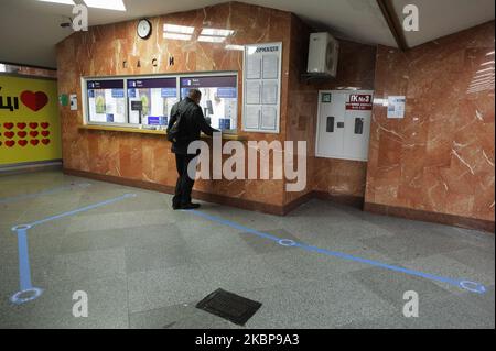 A lonely man buys a ticket at a Underground's ticket desk with a social distancing signs on the floor in Kyiv, Ukraine, May 25, 2020.The Ukrainian government allowed the resumption of the Kyiv underground system from 25 May, after over a two-month blockade imposed to slow the spread of the coronavirus pandemic. Passengers obliged to have their face masks on and keep social distancing. (Photo by Sergii Kharchenko/NurPhoto) Stock Photo