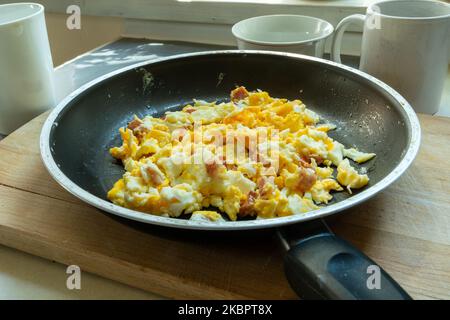 Morning scrambled eggs with bacon in a pan, close up Stock Photo