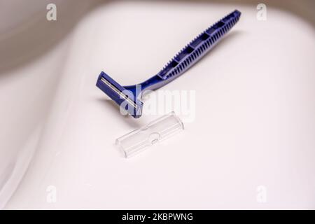 A disposable plastic blue razor lying on the sink Stock Photo