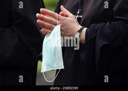 A nun holds a surgical mask while praying on Corpus Christi Holy Mass and procession during the spread of coronavirus. Krakow, Poland on 11 June, 2020. The procession starts with a priest carrying a monstrance under a canopy. The faithful follow him, singing religious hymns, while young girls dressed in white or traditional regional dresses scatter flower petals along the route. Corpus Christi is a Catholic moveable feast commemorating the Transubstitution. (Photo by Beata Zawrzel/NurPhoto) Stock Photo