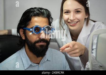 An eye doctor examines a male patient in a clinic with modern equipment. Stock Photo