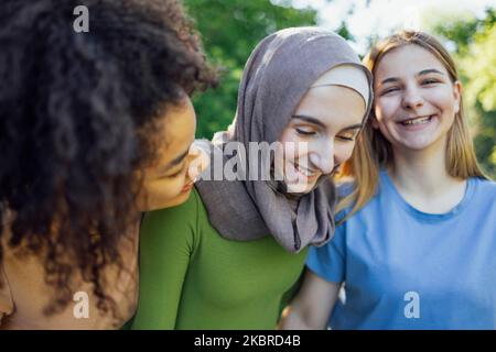 Multiracial young teen female friends walking in the park laughing and having fun together. Diversity and friendship concept Stock Photo