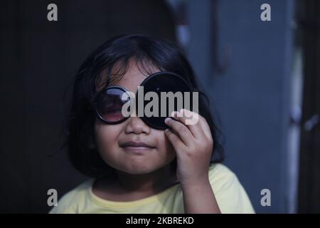 A girl watches the solar eclipse using a lens filter camera in Bogor, West Java, Indonesia, on June 21, 2020. (Photo by Adriana Adie/NurPhoto) Stock Photo