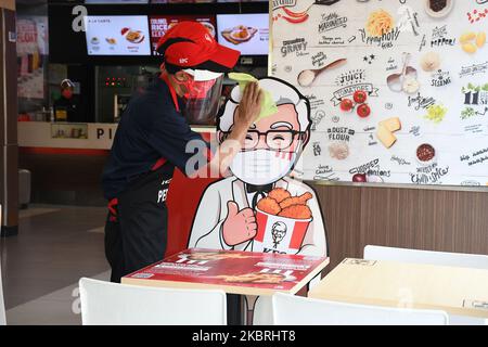 Waiters tidy up tables and draw KFC (Kentucky Fried Chicken) characters around tables and benches, in Salemba, Jakarta, on June, 24,2020. The character banner is used as a barrier for visitors who eat on the spot during the new normality phase. (Photo by Dasril Roszandi/NurPhoto) Stock Photo