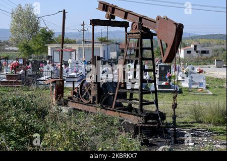 ALBANIA, Kuçova, named Stalin city from 1950 to1991, crude oil field and old drilling pump at cemetery, still operating and polluting the environment / ALBANIEN, Kucova, von 1950 bis 1991 Qyteti Stalin, Stalinstadt, Erdoelfoerderung, alte Oelfoerderpumpe, die heute noch zur Ölförderung in Betrieb sind, an einem Friedhof Stock Photo