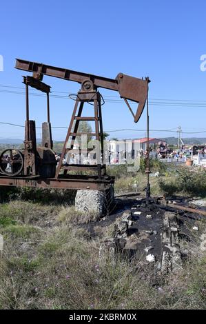 ALBANIA, Kuçova, named Stalin city from 1950 to1991, crude oil field and old drilling pump at cemetery, still operating and polluting the environment / ALBANIEN, Kucova, von 1950 bis 1991 Qyteti Stalin, Stalinstadt, Erdoelfoerderung, alte Oelfoerderpumpe, die heute noch zur Ölförderung in Betrieb sind, an einem Friedhof Stock Photo