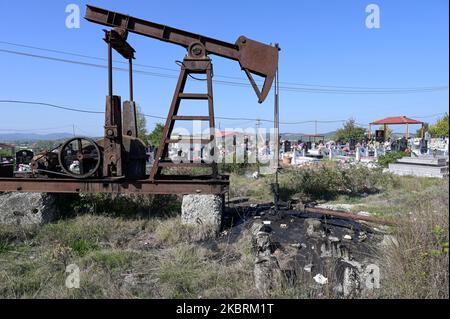 ALBANIA, Kuçova, named Stalin city from 1950 to1991, crude oil field and old drilling pump at cemetery, still operating and polluting the environment / ALBANIEN, Kucova, von 1950 bis 1991 Qyteti Stalin, Stalinstadt, Erdoelfoerderung, alte Oelfoerderpumpe, die heute noch zur Ölförderung in Betrieb sind, an einem Friedhof Stock Photo