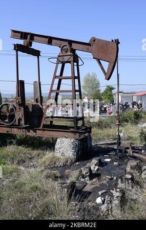 ALBANIA, Kuçova, named Stalin city from 1950 to1991, crude oil field and old drilling pump at cemetery, still operating and polluting the environment / ALBANIEN, Kucova, von 1950 bis 1991 Qyteti Stalin, Stalinstadt, Erdoelfoerderung, alte Oelfoerderpumpe, die heute noch zur Ölförderung in Betrieb sind, an einem Friedhof Stock Photo