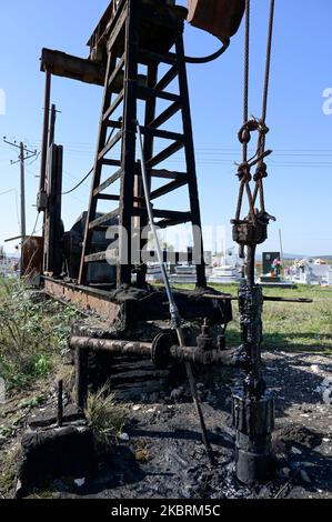 ALBANIA, Kuçova, named Stalin city from 1950 to1991, crude oil field and old drilling pump at cemetery, still operating and polluting the environment / ALBANIEN, Kucova, von 1950 bis 1991 Qyteti Stalin, Stalinstadt, Erdoelfoerderung, alte Oelfoerderpumpe, die heute noch zur Ölförderung in Betrieb sind, an einem Friedhof Stock Photo