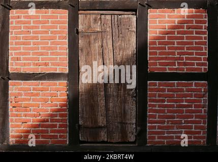 Old door in rustic brick wall, diagonal shadow Stock Photo