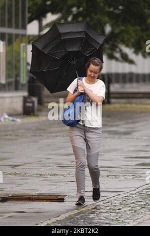A woman tries to hold on to her umbrella while a gust of wind blows it inside out on June 29, 2020 in Warsaw, Poland. Due to heavy rains several roads in the city have been partly submerged causing. traffic to be rerouted and leading to traffic jams several kilometers long. After a long spell of drought Poland has suffered heavy rains in the past couple of weeks. (Photo by Jaap Arriens/NurPhoto) Stock Photo