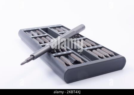 Precision metal, gray screwdriver and a set of interchangeable bits in a dedicated box on a white background Stock Photo