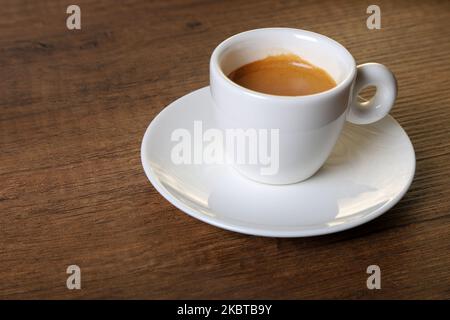White cup of espresso with coffee beans on wooden background,top view Stock Photo