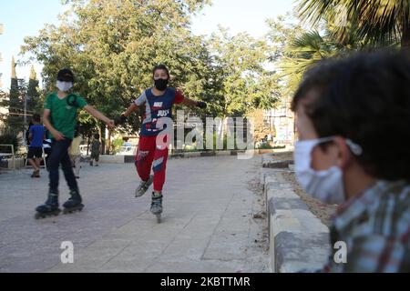 Syrian children play with skateboards in Idlib, northwestern Syria, wearing protective masks to prevent coronavirus, as the number of cases infected with the virus in Idlib reached 13 on July 18, 2020. (Photo by Muhammad al-Rifai/NurPhoto) Stock Photo