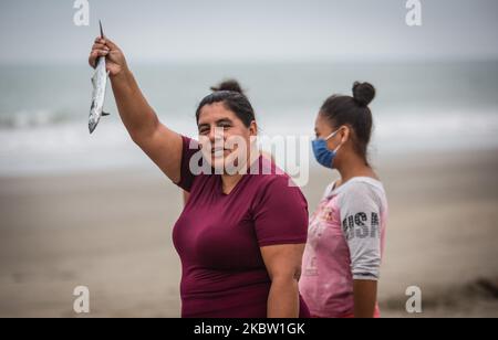 The citizens of Tonsupa in the province of Esmeraldas Ecuador, on July 21, 2020, remains in constant fear of the new SARS COV2 virus, on this beach request government help to cope with the food and economic need that arose in this Andean country after it remains in almost four months in quarantine. In view of the fact that the Lenin Moreno government does not do something or offer help, several fishermen go out to sea to fish and then reach the shore and supply the most needy, they assure that they will get ahead as usual. Several citizens push the canoes that go out to do this work in gratitu Stock Photo