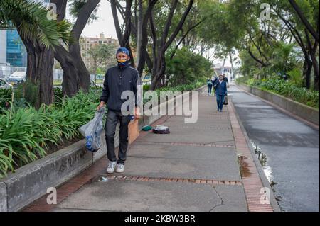 A venezuelan migrant recollects leaves from trees on the street while using a protective face mask with the Venezuelan flag during the sectorized lockdowns amid the novel Coronavirus pandemic in Bogota, Colombia, on July 22, 2020. (Photo by Sebastian Barros/NurPhoto) Stock Photo
