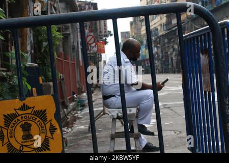 Indian traffic police watch on his smart phoneÂ live news at the a deserted street as the state authorities have imposed two days of lockdown each week to fight against the surge in COVID-19 coronavirus cases, in Kolkata on July 25, 2020.India is the third hardest-hit country by the pandemic in the world after the United States and Brazil. (Photo by Debajyoti Chakraborty/NurPhoto) Stock Photo