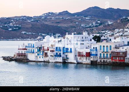 Magic hour during sunset and dusk at Little Venice in Mykonos island, one of the most romantic places in the Mediterranean island on July 14, 2020. This neighborhood is replete with elegant and gorgeous old houses that are situated precariously on the edge of the Aegean Sea, colorful two-story Venetian style buildings with wooden balconies. These buildings now house trendy bars, restaurants, galleries and more but their exterior is still one of the most popular favorite sunset spots, the classic romantic Mykonos experience. The famous island in the Cyclades is nicknamed as The Island of the Wi Stock Photo