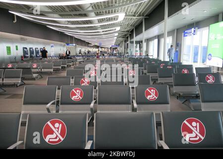 Passengers waiting with facemask, checking in at the counter for boarding and empty seats with signs blocking them inside the gates area with reduced traffic. Flying from Athens International Airport ATH LGAV in Greece. Passengers with facemasks and protective measures as gloves, hand sanitizer, blocking seats, applying social distancing, distance signs etc because of the Coronavirus Covid-19 Pandemic outbreak, safety measures, as seen at the check-in counters, main departure terminal, at the gates. Athens, Greece - July 2020 (Photo by Nicolas Economou/NurPhoto) Stock Photo