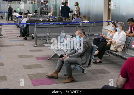 Passengers waiting with facemask, checking in at the counter for boarding and empty seats with signs blocking them inside the gates area with reduced traffic. Flying from Athens International Airport ATH LGAV in Greece. Passengers with facemasks and protective measures as gloves, hand sanitizer, blocking seats, applying social distancing, distance signs etc because of the Coronavirus Covid-19 Pandemic outbreak, safety measures, as seen at the check-in counters, main departure terminal, at the gates. Athens, Greece - July 2020 (Photo by Nicolas Economou/NurPhoto) Stock Photo