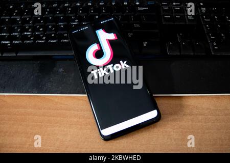 TikTok closeup logo displayed on a phone screen, smartphone and keyboard are seen in this multiple exposure illustration. Tik Tok is a Chinese video-sharing social networking service owned by a Beijing based internet technology company, ByteDance. It is used to create short dance, lip-sync, comedy and talent videos. ByteDance launched TikTok app for iOS and Android in 2017 and earlier in September 2016 Douyin fror the market in China. TikTok became the most downloaded app in the US in October 2018. President of the USA Donald Trump is threatening and planning to ban the popular video sharing a Stock Photo