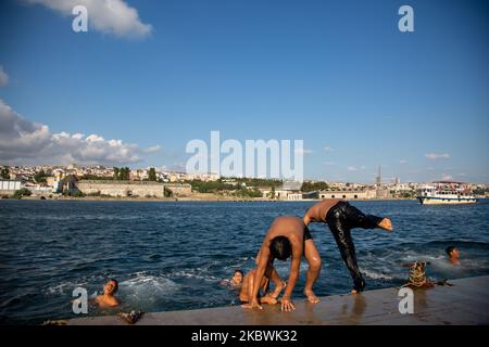 People jump into the Bosphorus to cool off as he enjoy the warm weather during the second day of the celebrations of the Eid-al-Adha in Istanbul, Turkey, 01 August 2020. Eid al-Adha is the holiest of the two Muslims holidays celebrated each year, it marks the yearly Muslim pilgrimage (Hajj) to visit Mecca, the holiest place in Islam. Muslims slaughter a sacrificial animal and split the meat into three parts, one for the family, one for friends and relatives, and one for the poor and needy. (Photo by Fayed El-Geziry/NurPhoto) Stock Photo