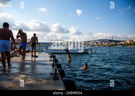 People jump into the Bosphorus to cool off as he enjoy the warm weather during the second day of the celebrations of the Eid-al-Adha in Istanbul, Turkey, 01 August 2020. Eid al-Adha is the holiest of the two Muslims holidays celebrated each year, it marks the yearly Muslim pilgrimage (Hajj) to visit Mecca, the holiest place in Islam. Muslims slaughter a sacrificial animal and split the meat into three parts, one for the family, one for friends and relatives, and one for the poor and needy. (Photo by Fayed El-Geziry/NurPhoto) Stock Photo