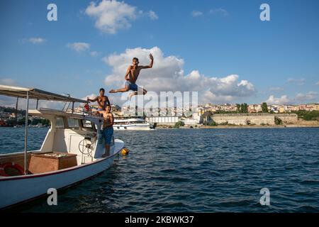 People jump into the Bosphorus to cool off as he enjoy the warm weather during the second day of the celebrations of the Eid-al-Adha in Istanbul, Turkey, 01 August 2020. Eid al-Adha is the holiest of the two Muslims holidays celebrated each year, it marks the yearly Muslim pilgrimage (Hajj) to visit Mecca, the holiest place in Islam. Muslims slaughter a sacrificial animal and split the meat into three parts, one for the family, one for friends and relatives, and one for the poor and needy. (Photo by Fayed El-Geziry/NurPhoto) Stock Photo