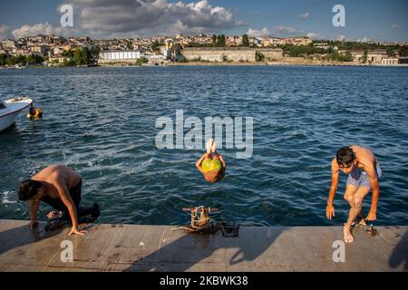 People jump into the Bosphorus to cool off as he enjoy the warm weather during the second day of the celebrations of the Eid-al-Adha in Istanbul, Turkey, 01 August 2020. Eid al-Adha is the holiest of the two Muslims holidays celebrated each year, it marks the yearly Muslim pilgrimage (Hajj) to visit Mecca, the holiest place in Islam. Muslims slaughter a sacrificial animal and split the meat into three parts, one for the family, one for friends and relatives, and one for the poor and needy. (Photo by Fayed El-Geziry/NurPhoto) Stock Photo