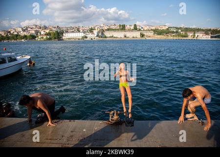 People jump into the Bosphorus to cool off as he enjoy the warm weather during the second day of the celebrations of the Eid-al-Adha in Istanbul, Turkey, 01 August 2020. Eid al-Adha is the holiest of the two Muslims holidays celebrated each year, it marks the yearly Muslim pilgrimage (Hajj) to visit Mecca, the holiest place in Islam. Muslims slaughter a sacrificial animal and split the meat into three parts, one for the family, one for friends and relatives, and one for the poor and needy. (Photo by Fayed El-Geziry/NurPhoto) Stock Photo