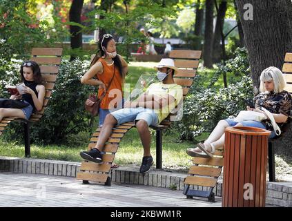People rest on benches at a park at a sunny day in Kyiv, Ukraine, on 03 August, 2020. New rules of adaptive quarantine due the COVID-19 coronavirus spread shall be applied in Ukraine, the country's cities and districts are divided into 4 zones depending on the epidemiological situation, as local media reported. (Photo by STR/NurPhoto) Stock Photo