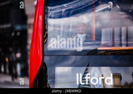 A man wearing a face mask rides a bus through Bank Junction in the City of London financial district in London, England, on August 5, 2020. This week has been the first of the government push to get workers in England back to their offices, though many nonetheless remain working from home as the country continues its cautious emergence from the coronavirus lockdown. (Photo by David Cliff/NurPhoto) Stock Photo