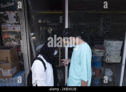 An Iranian man and a woman wearing protective face masks use a smartphone while standing on a street-side in Tehran’s business district, following the new coronavirus (COVID-19) outbreak in Iran. (Photo by Morteza Nikoubazl/NurPhoto) Stock Photo