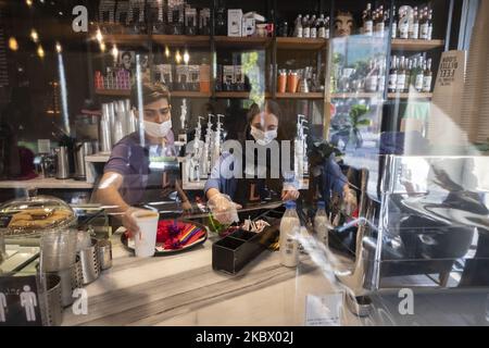 An Iranian cafe-man and cafe-woman wearing protective face masks work at a cafe in northern Tehran, Iran, on August 9, 2020 following the new coronavirus (COVID-19) outbreak in Iran. (Photo by Morteza Nikoubazl/NurPhoto) Stock Photo