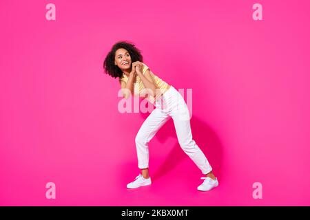 Full size photo of young adorable pretty woman pull abstract object look empty space interested information isolated on pink color background Stock Photo