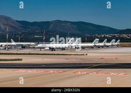 The grounded Airbus A320 family fleet of passenger aircraft of Aegean Airlines as seen parked at Athens International Airport ATH LGAV in the Greek capital. Aegean Airlines is the flag carrier of Greece based with a hub in Athens. The airplanes are not flying due to the Covid pandemic outbreak. Many of the planes have their jet engines covered with a red cover. Covid-19 cases skyrocket in Greece the past few days as tourists and locals are more relaxed without keeping the social distancing and mandatory safety measures such as protective mask during their summer holidays in tourist destination Stock Photo