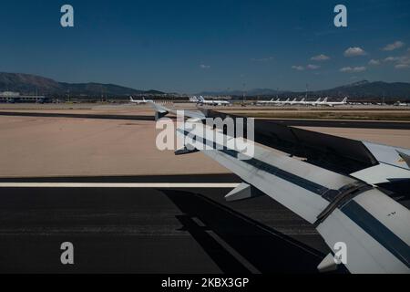 The grounded Airbus A320 family fleet of passenger aircraft of Aegean Airlines as seen over a wing of an airplane, parked at Athens International Airport ATH LGAV in the Greek capital. Aegean Airlines is the flag carrier of Greece based with a hub in Athens. The airplanes are not flying due to the Covid pandemic outbreak. Many of the planes have their jet engines covered with a red cover. Covid-19 cases skyrocket in Greece the past few days as tourists and locals are more relaxed without keeping the social distancing and mandatory safety measures such as protective mask during their summer hol Stock Photo