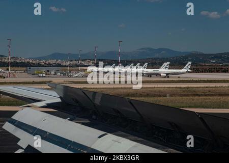 The grounded Airbus A320 family fleet of passenger aircraft of Aegean Airlines as seen over a wing of an airplane, parked at Athens International Airport ATH LGAV in the Greek capital. Aegean Airlines is the flag carrier of Greece based with a hub in Athens. The airplanes are not flying due to the Covid pandemic outbreak. Many of the planes have their jet engines covered with a red cover. Covid-19 cases skyrocket in Greece the past few days as tourists and locals are more relaxed without keeping the social distancing and mandatory safety measures such as protective mask during their summer hol Stock Photo