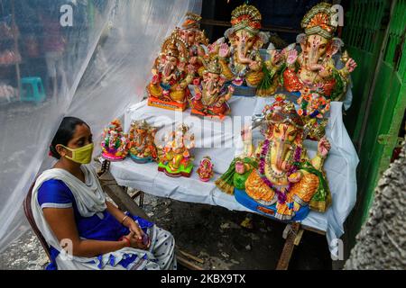 A lady wearing mask waits for customer for the Ganesha idols ahead of Ganesh puja at a potters hub in Kolkata.Ganesh chaturthi or Ganesh puja is the Hindu festival of celebrating the arrival of Lord Ganesha, the Elephant headed deity of Hindu mythology from Kailash parvaat to earth. People decorate their houses with flowers and ornaments and bring Ganesha idols to worship during this time. This year , the festivities took a hit and showed a decline due to COVID-19 outbreak , forcing peoples into cash crunch. The idol makers and sellers are facing a tough time in the potters hub of Kolkata due  Stock Photo